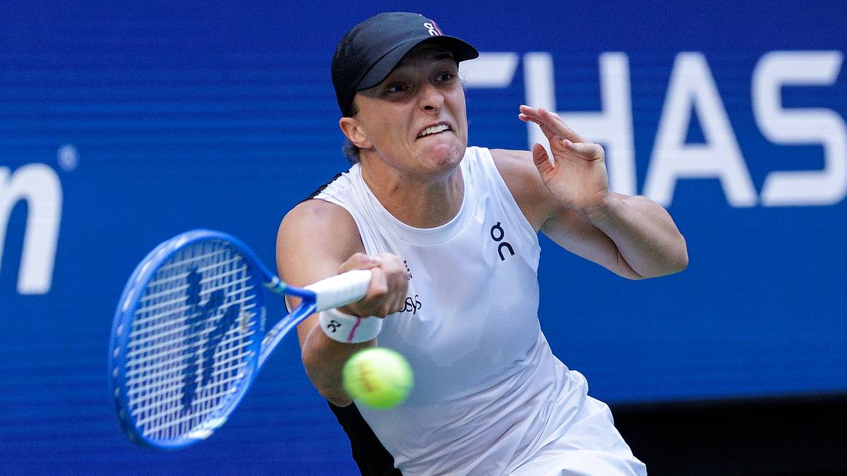 Iga Świątek podczas meczu tenisowego, uderza piłkę rakietą.