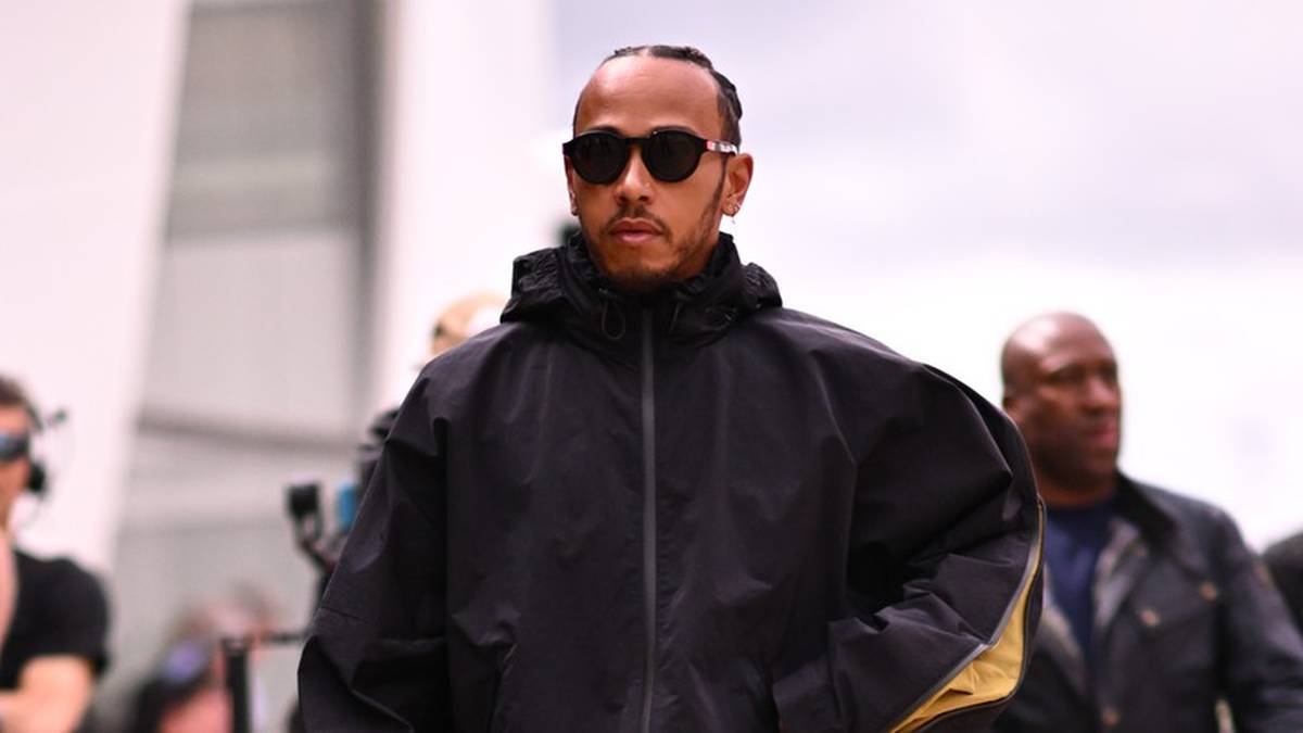 Lewis Hamilton, kierowca Formuły 1, w czarnej kurtce i okularach przeciwsłonecznych.