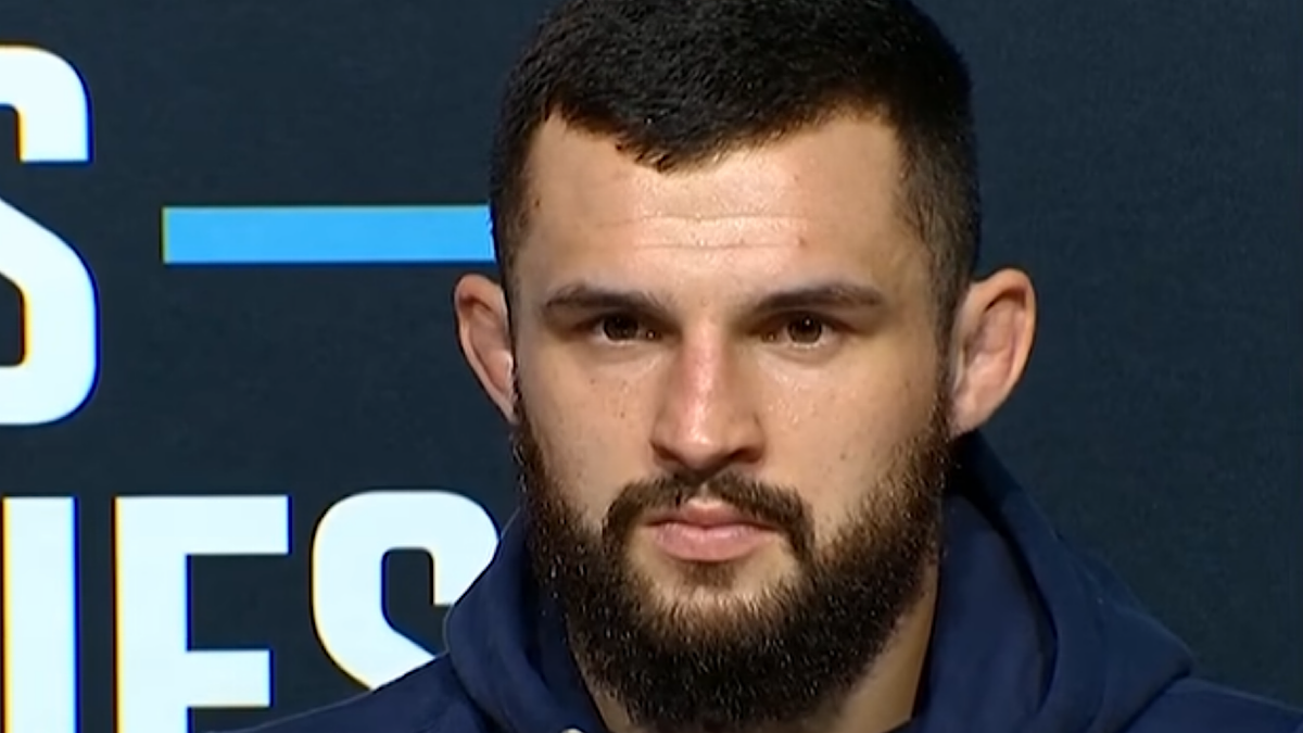 Mężczyzna z brodą i ciemnymi włosami, patrzący prosto przed siebie.