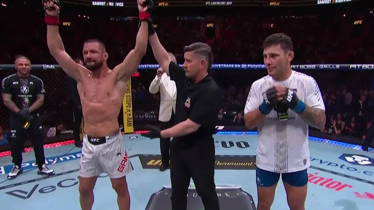 Mateusz Gamrot wznosi ręce w geście zwycięstwa, obok niego stoi sędzia i pokonany Esteban Ribovics.